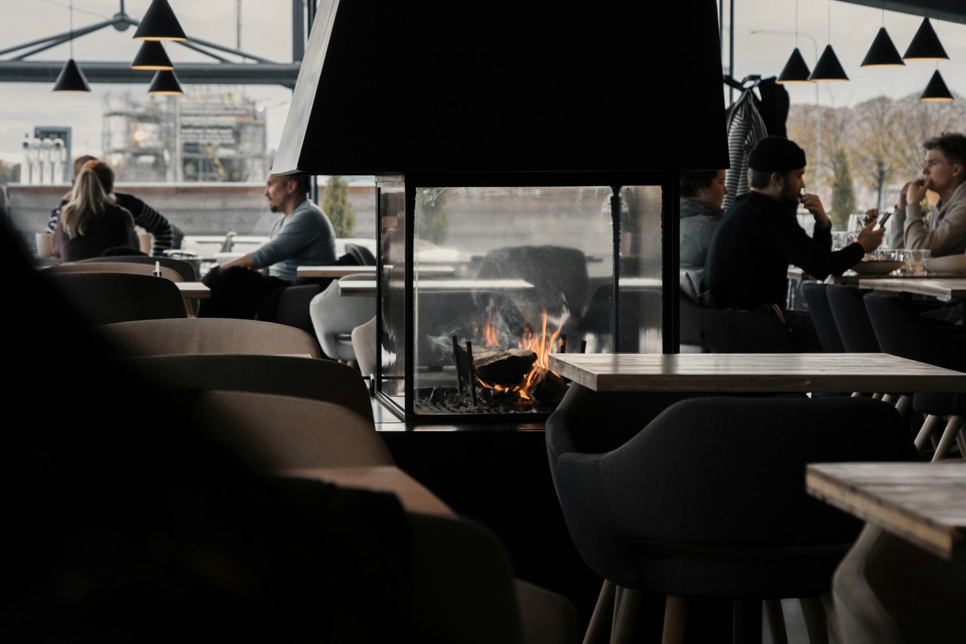Des gens sont assis sur des chaises près d'un foyer extérieur en plein jour.
