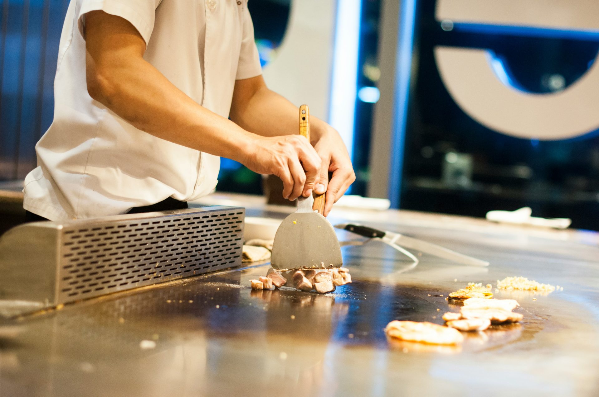 Un chef cuisinier prépare de la viande sur une plaque de cuisson.